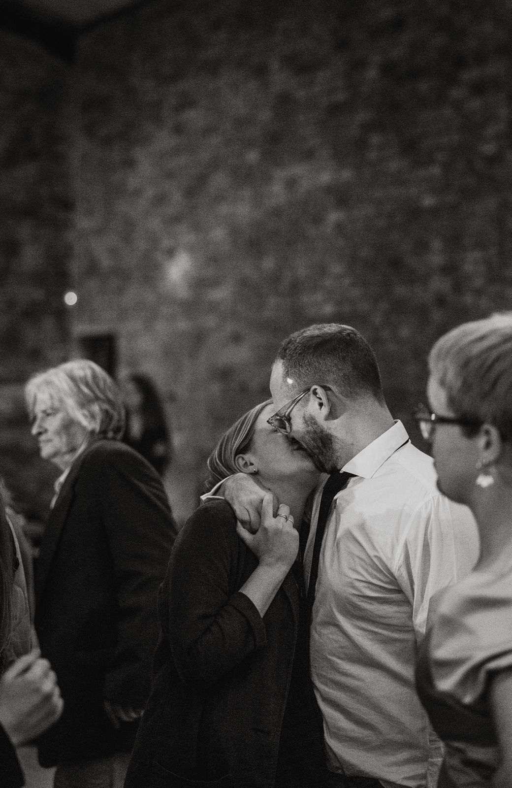 Two people kissing at a social event with a blurred background