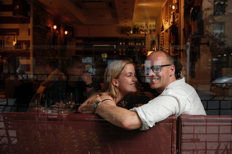 Couple sitting close together in a dimly lit bar or restaurant.