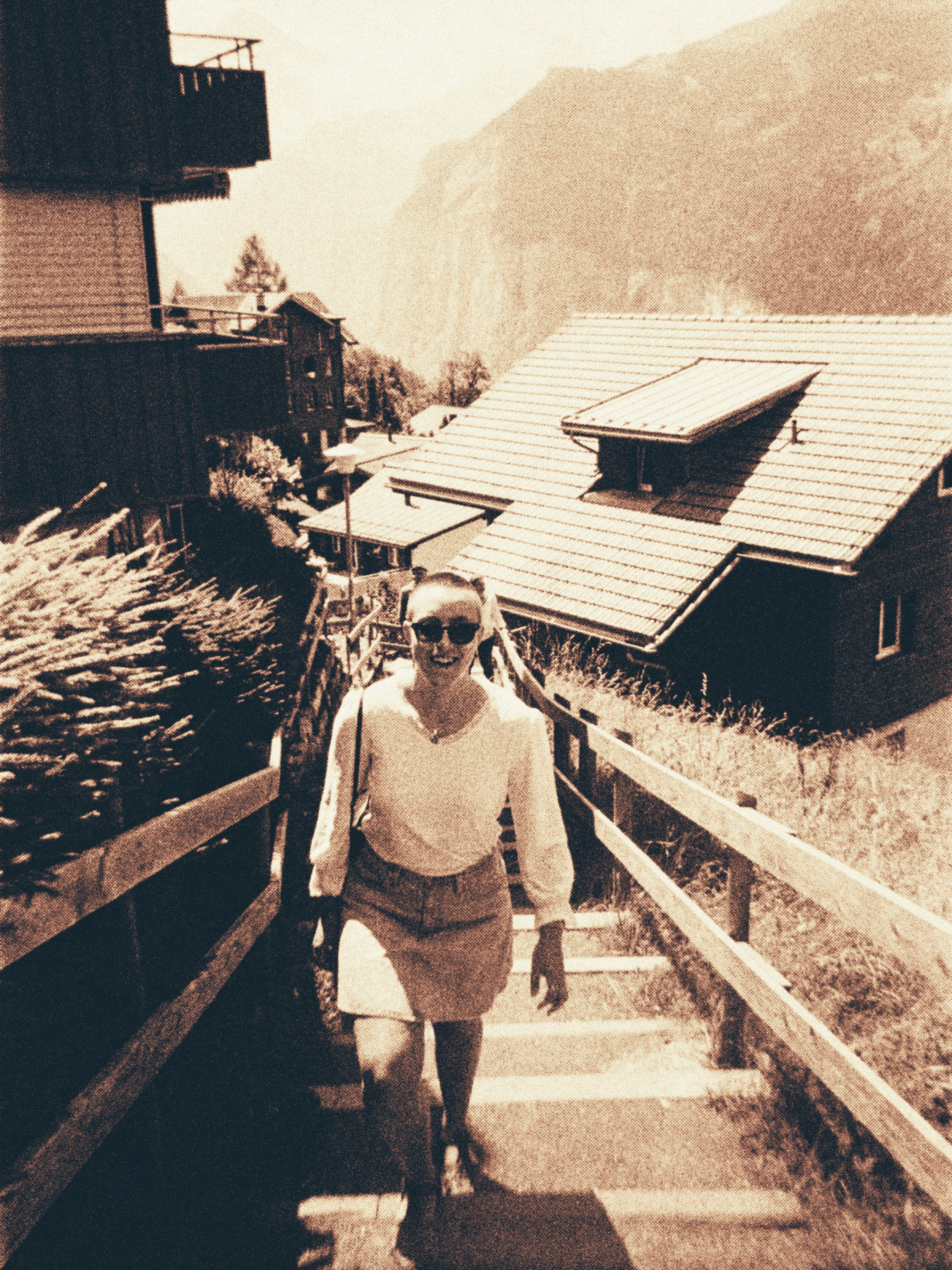Woman walking up a set of stairs in a mountain village with wooden houses.