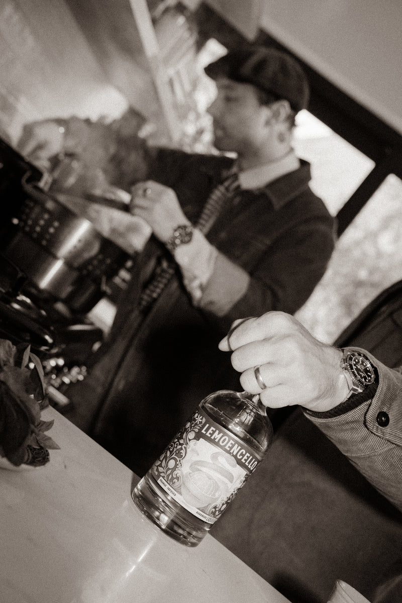 Man pouring a drink from a Lemoencello  bottle in the kitchen.