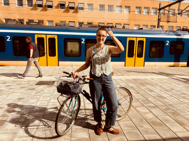 Woman with a bicycle giving a thumbs-up in front of a train