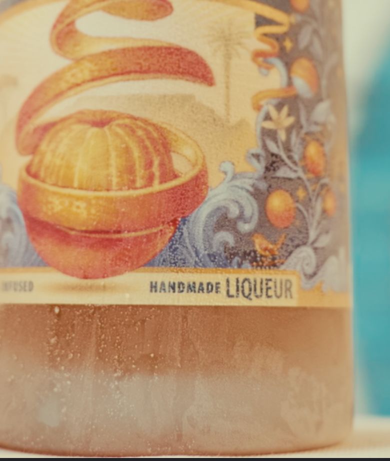 Close-up of a Lemoencello bottle label with an orange design and 'Handmade Liqueur' text.