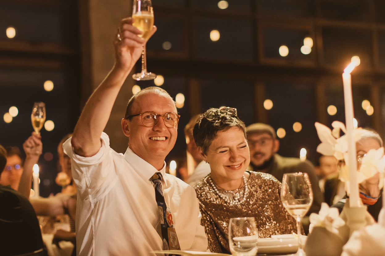 Man and woman at a formal event, raising glasses with a night-time outdoor setting.