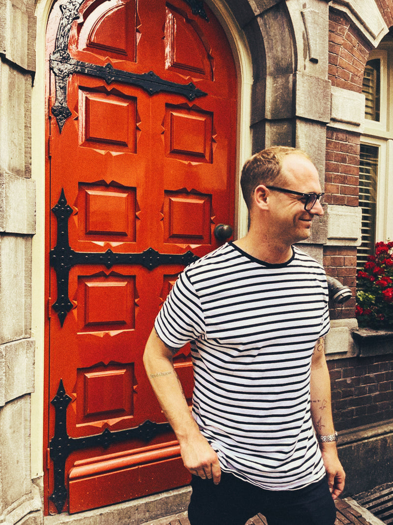 Danie du Toit in a striped shirt standing in front of a red door