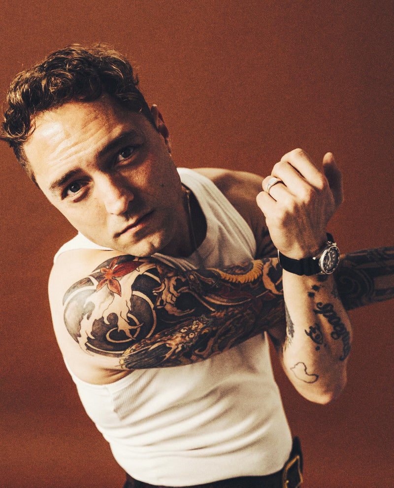Man with tattoos on his arms against a warm-toned background