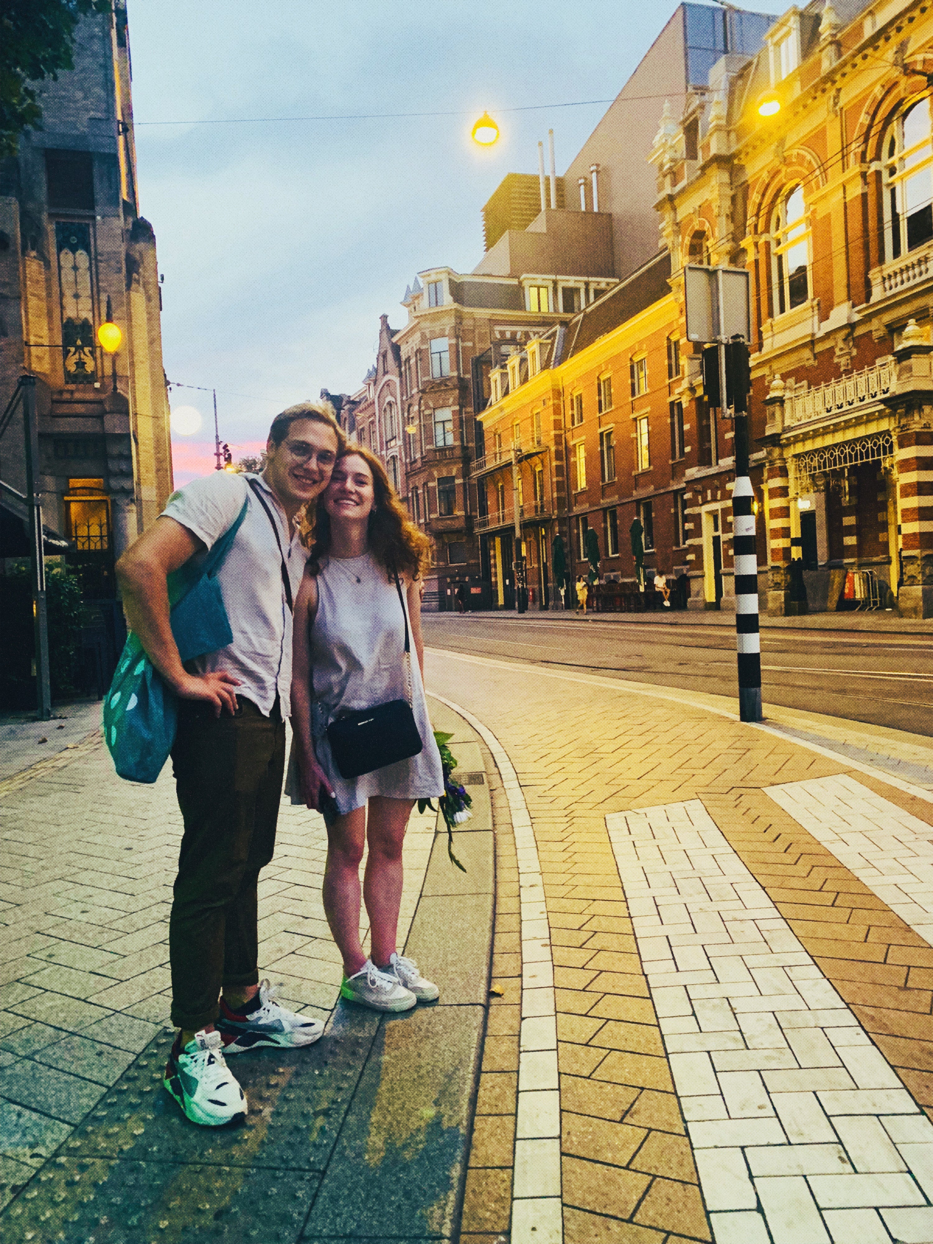 A couple standing on a city street in Amsterdam with historic buildings in the background